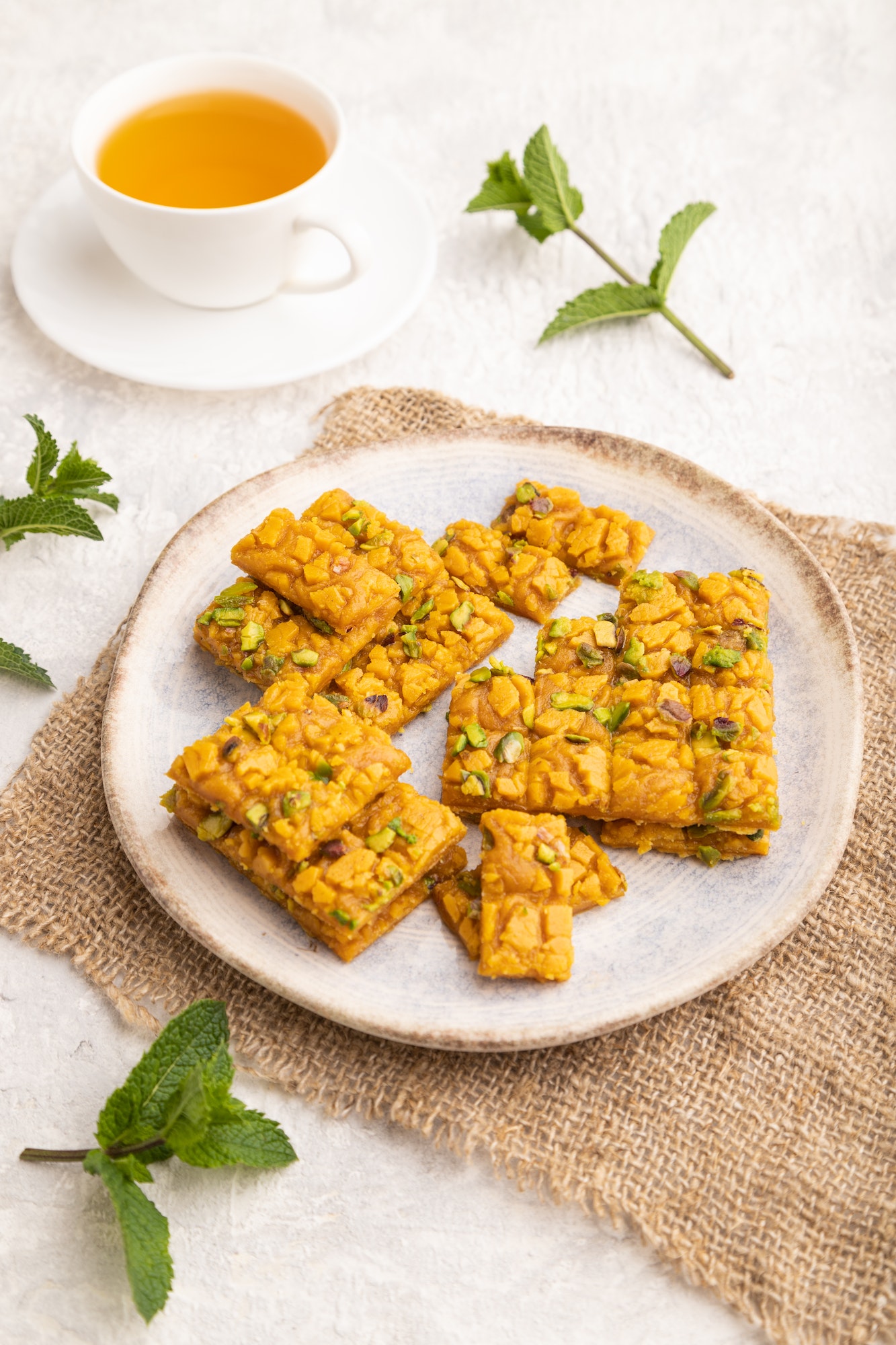 Traditional iranian dessert sohan with cup of green tea on a gray concrete background